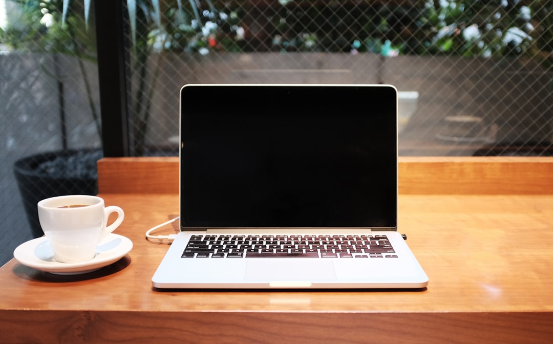 Laptop showing pricing comparison page with a coffee cup on a wooden desk